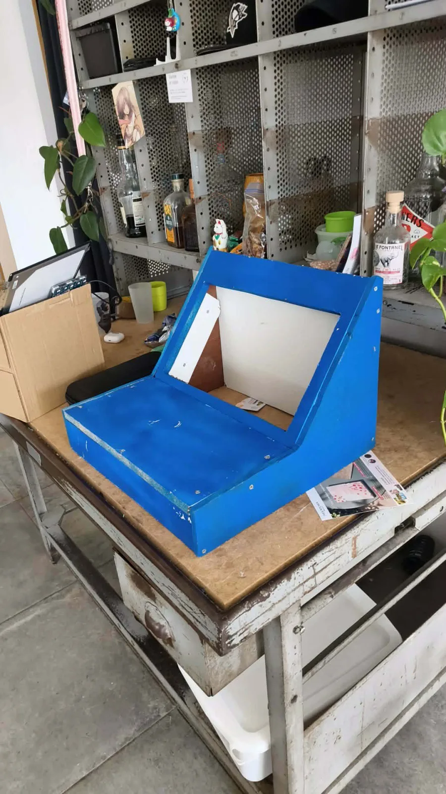 The cabinet's wooden parts painted blue and laid out on a protective sheet