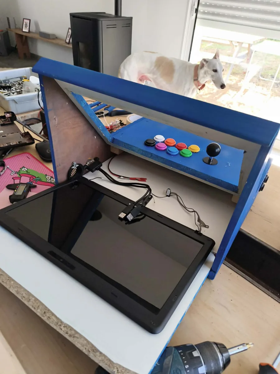 The completed blue wooden arcade cabinet with a joystick and colorful buttons